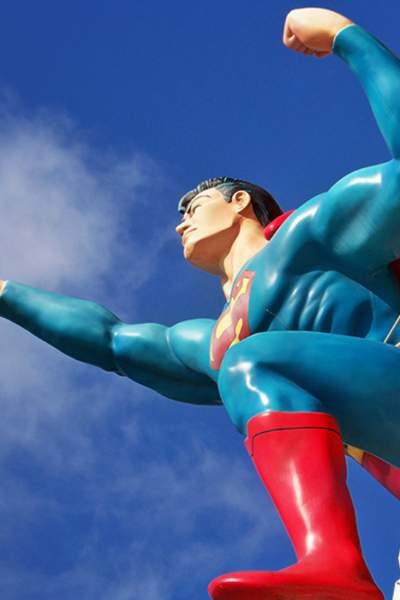 A statue of superman against a blue sky