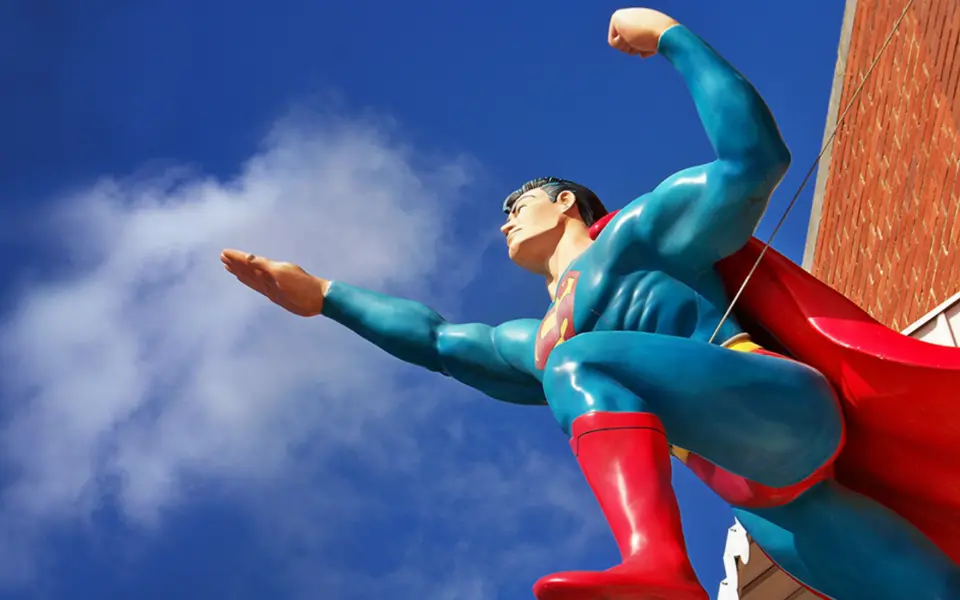 A statue of superman against a blue sky