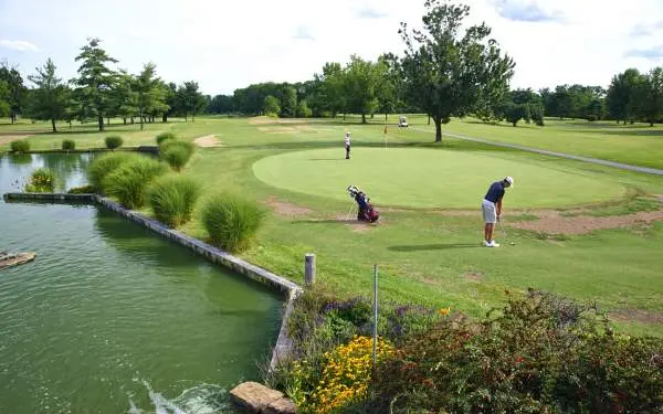 Golfers playing a round on a green, next to a water feature