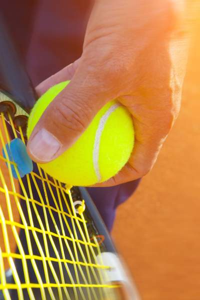 A close up of someone getting ready to serve a tennis ball