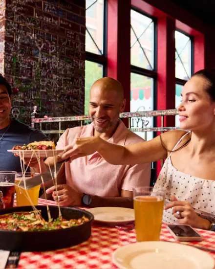 Friends sharing pizza and drinks at a restaurant.