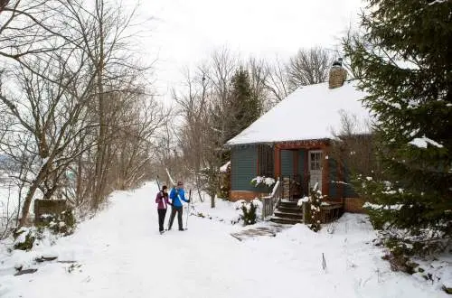 Two people in the snow walking into a cabin