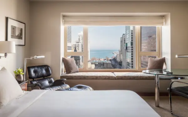 Hotel room with a big window looking out into the city.