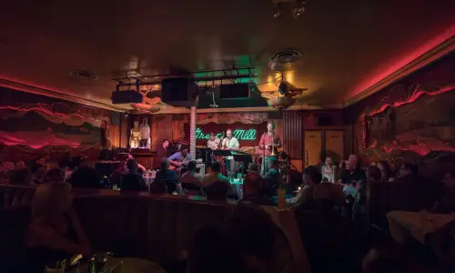 A band plays in a dimly lit room in the green mill speakeasy