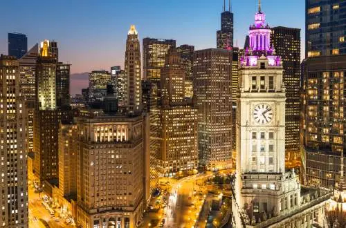 Aerial view of Chicago skyscrapers at twilight, with Wrigley Building in foreground.
