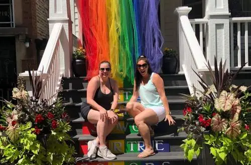 Girls standing in front of pride flag.