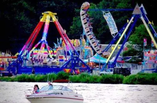 Festival rides in the background with a river and boat out