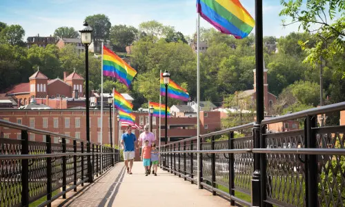 People walking down the bridge with flags along it