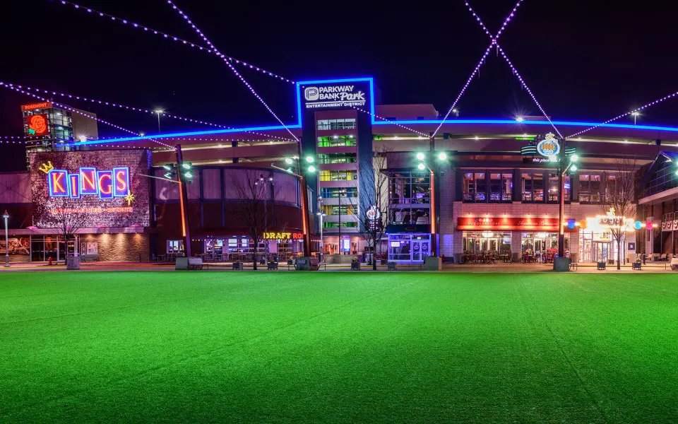 The entry way to a large building with fake grass in front and lots of lights