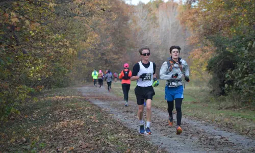 Runners race on an outdoor track in fall