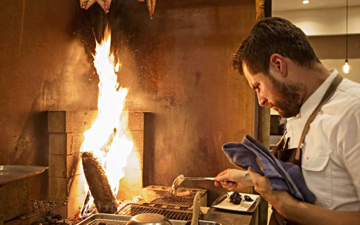 A chef cooks over flames in Smyth's open kitchen