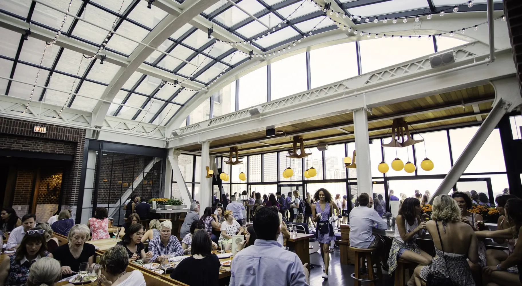 A crowd of people beneath the glass atrium of Cindy's rooftop bar