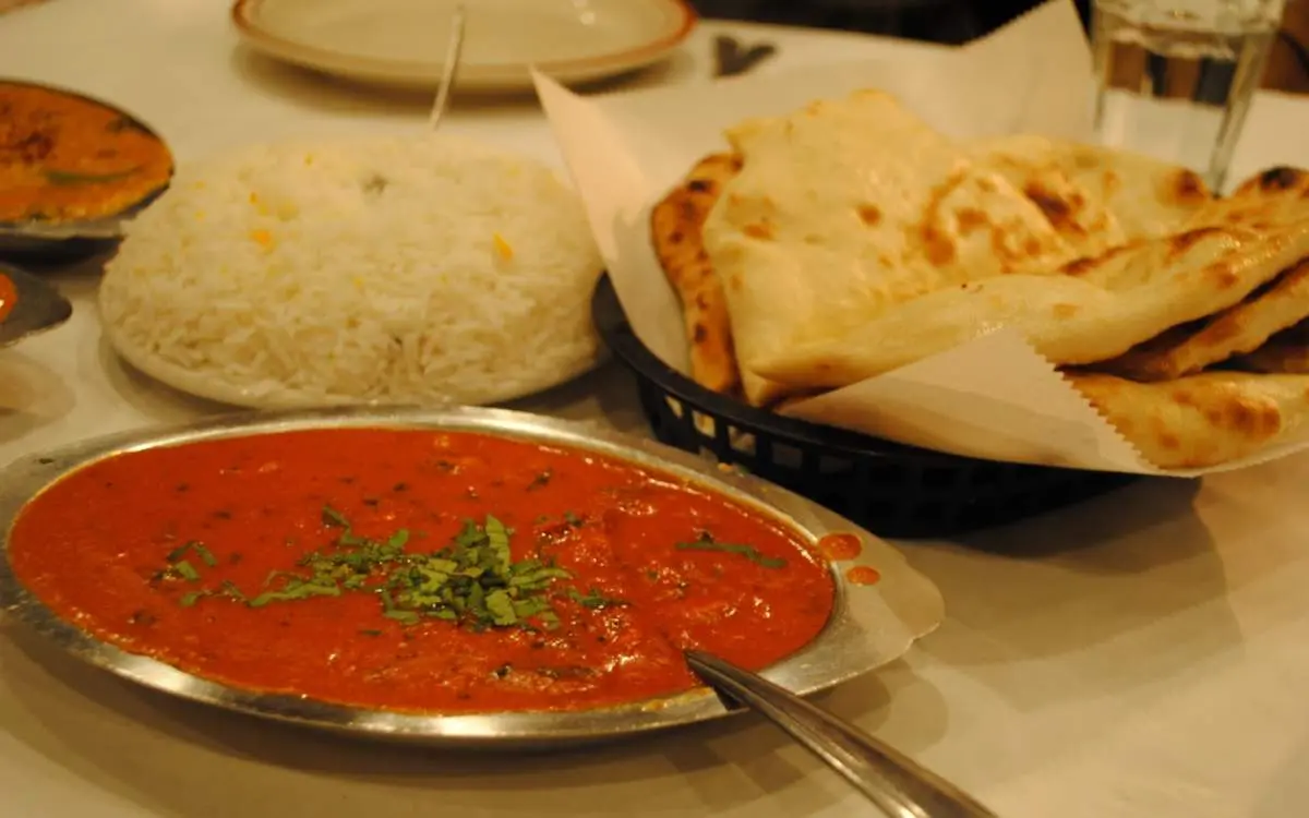 An indian curry, plate of rice and naan bread