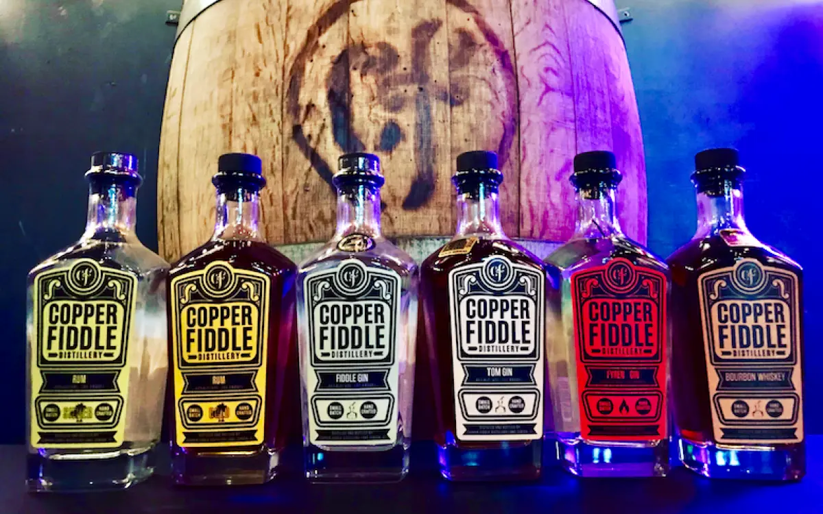 Alcohol bottles in a line with a barrel behind it