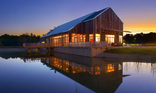 A photo of the Firefly grill during sunset with the lake reflecting the building.