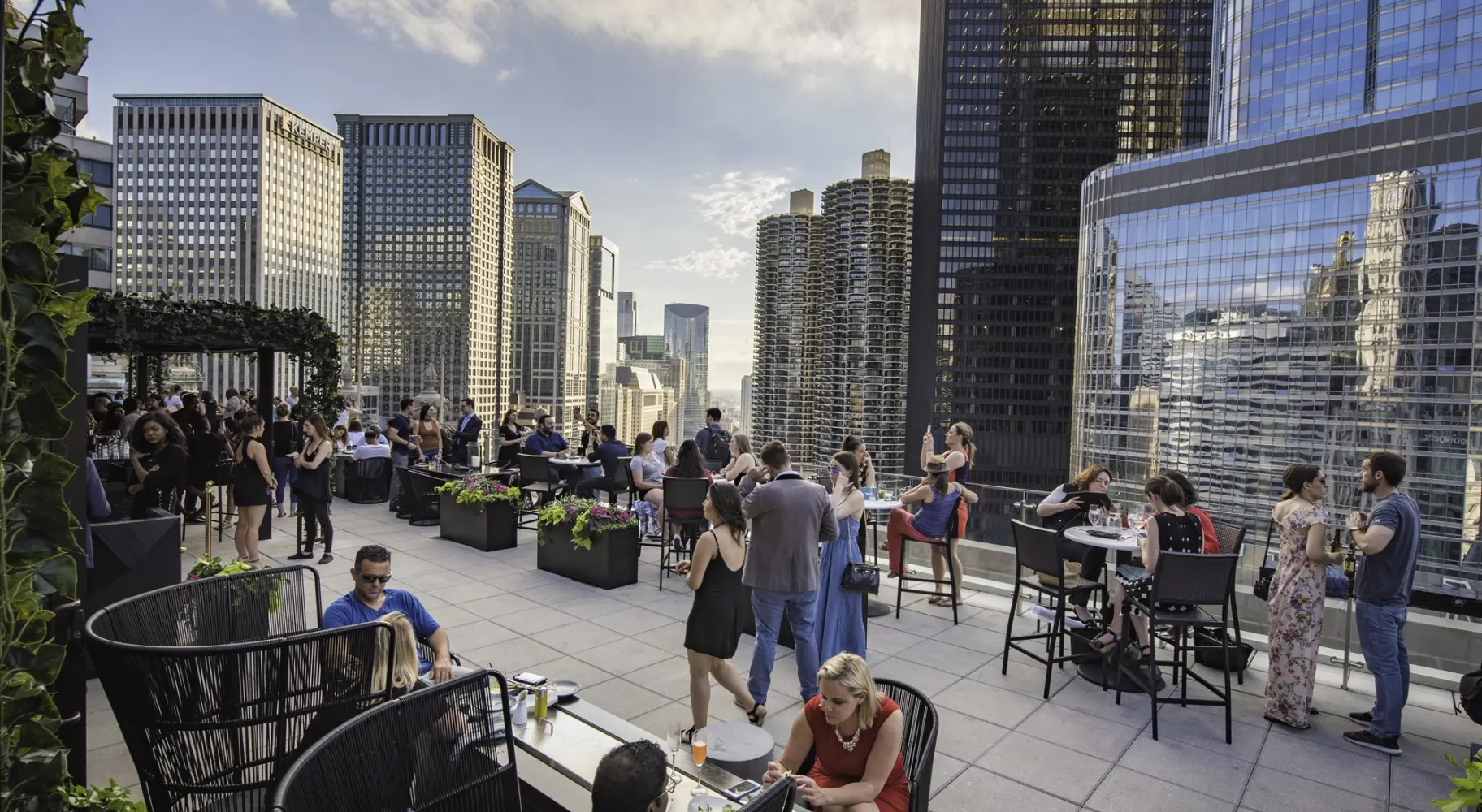 People gathered at a rooftop bar amid the tops of skyscrapers