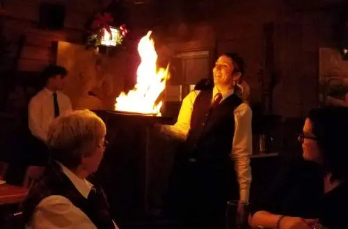 A waitress with a flaming plate at Log Cabin Steakhouse
