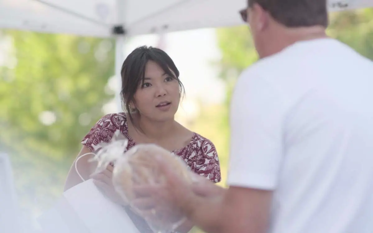 Jojo Gendenbaatar of Crust and Crumbles talking with a customer at her market stall