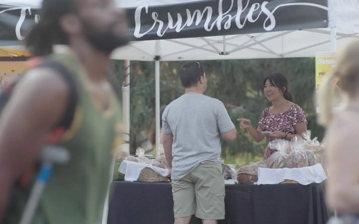 Jojo Gendenbaatar of Crust and Crumbles talking with a customer at her market stall