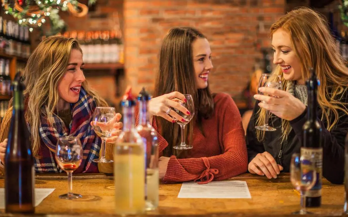 Three women sitting at a table enjoying a glass of wine inside of a wine cellar