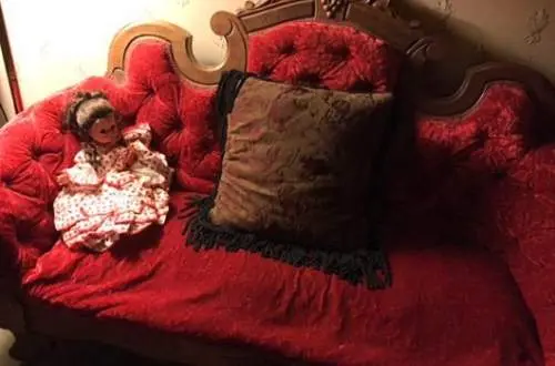 A red couch with a doll on it