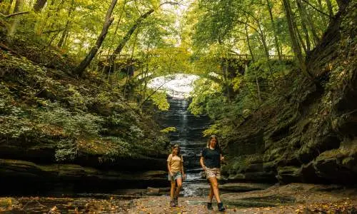 Two girls walk in front of a waterfall at Matthiessen State Park