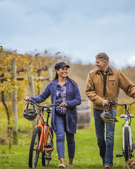 A couple walking with their bikes through the vines