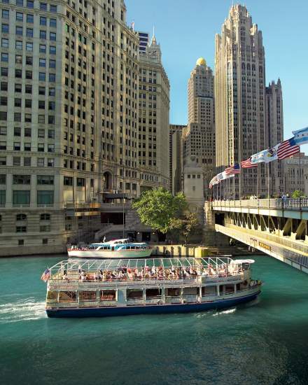 An architecture river tour boat passes under a bridge in Chicago