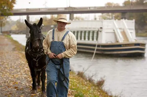 Man leading a donkey and a canal boat