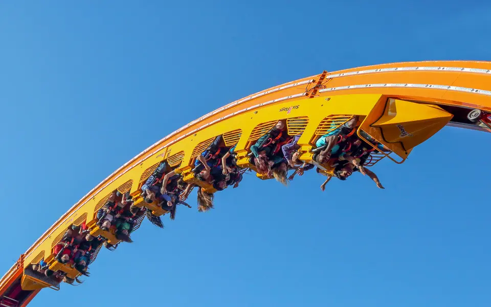 Group of people riding the roller coaster in mid air.