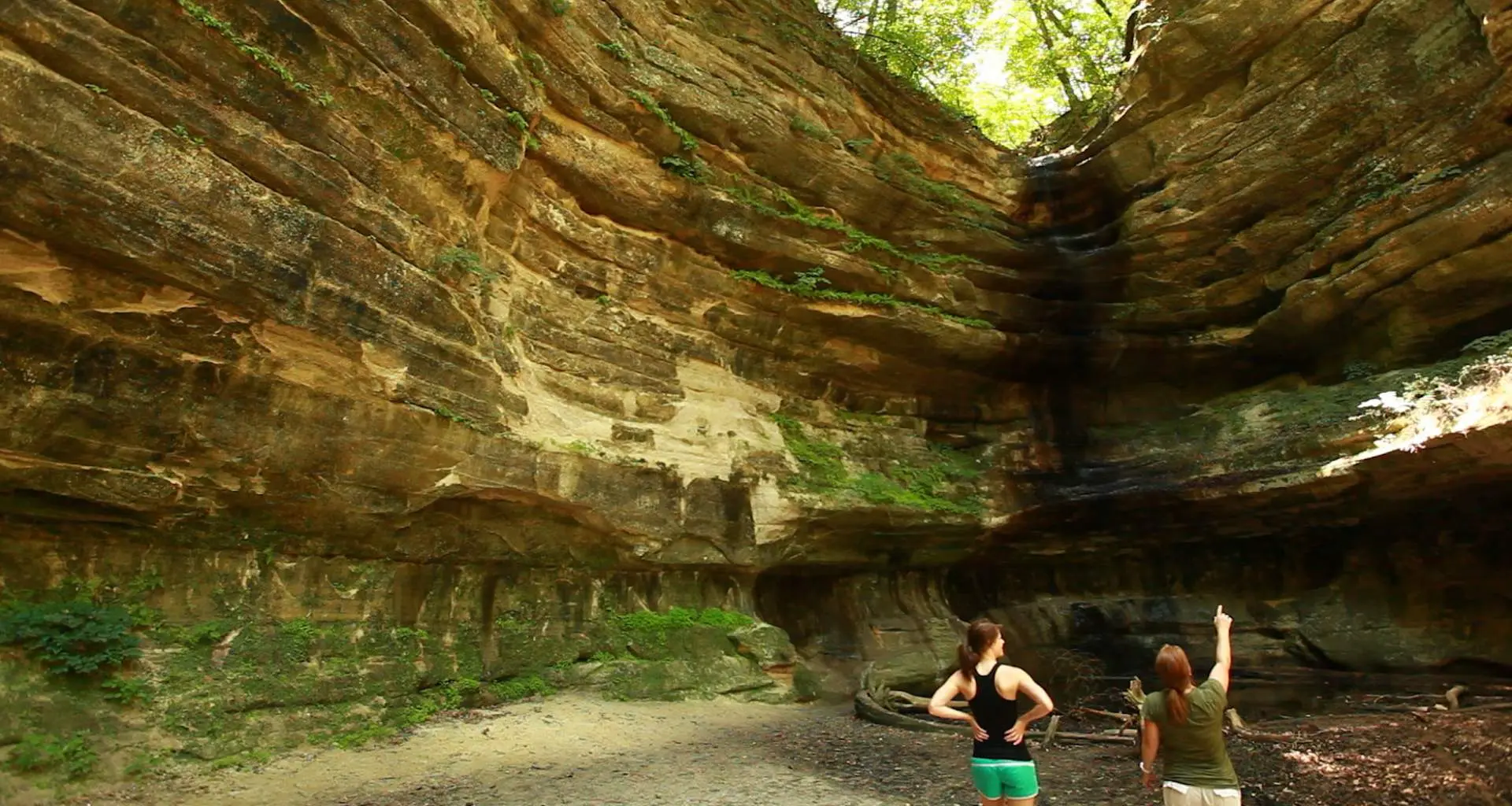 Two people looking up at the large rock surrounding