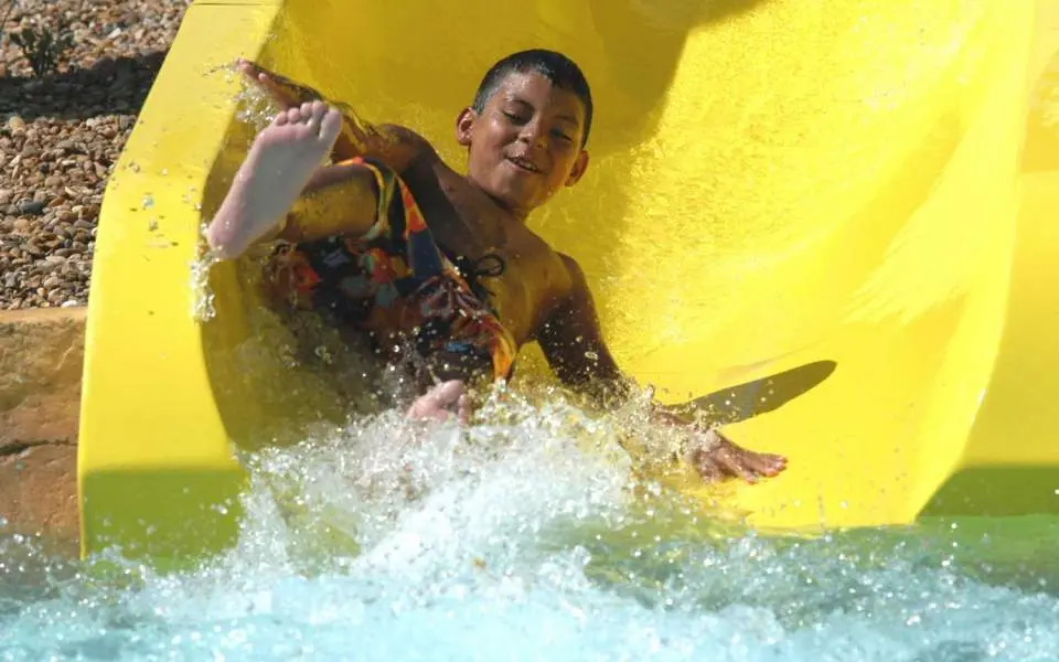 Child coming down yellow Great America Hurricane Harbor water slide