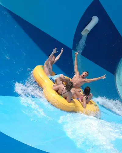 A group of four people in an inflatable raft on a water slide