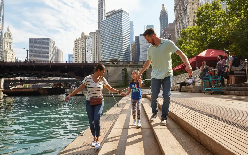 Family waking by a river with city in the background