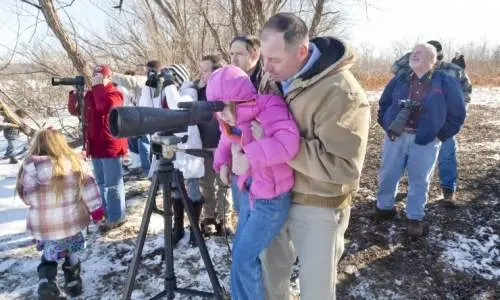 People looking through large camera lense