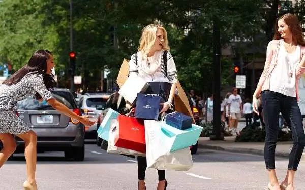 Woman with a handful of shopping bags in the middle of a pedestrian crossing.