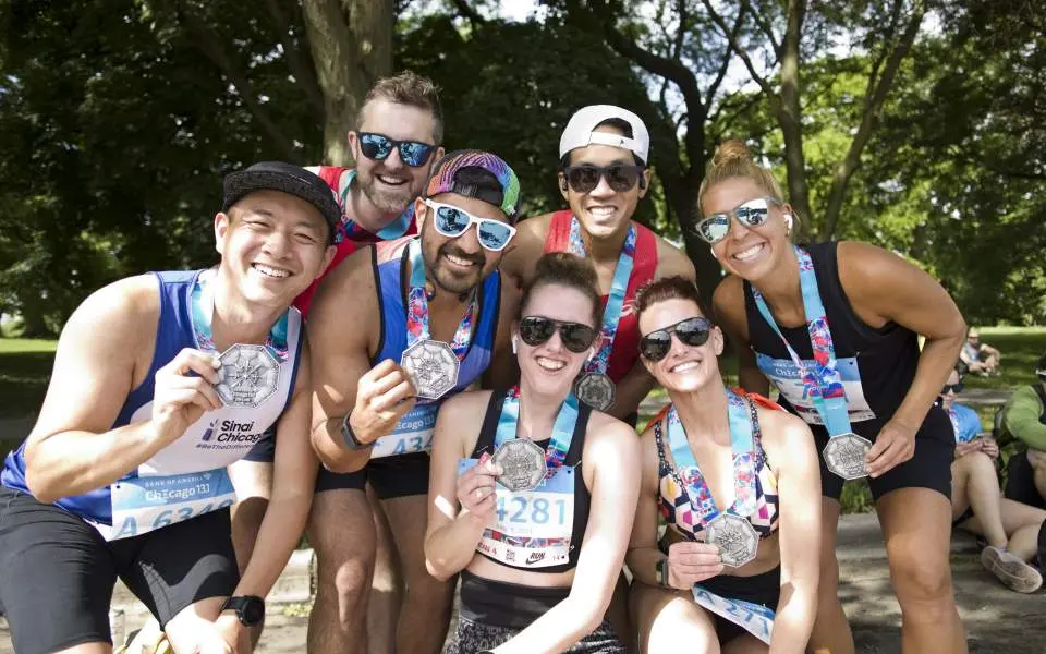 A group of marathon runners holding up participant medals after a race